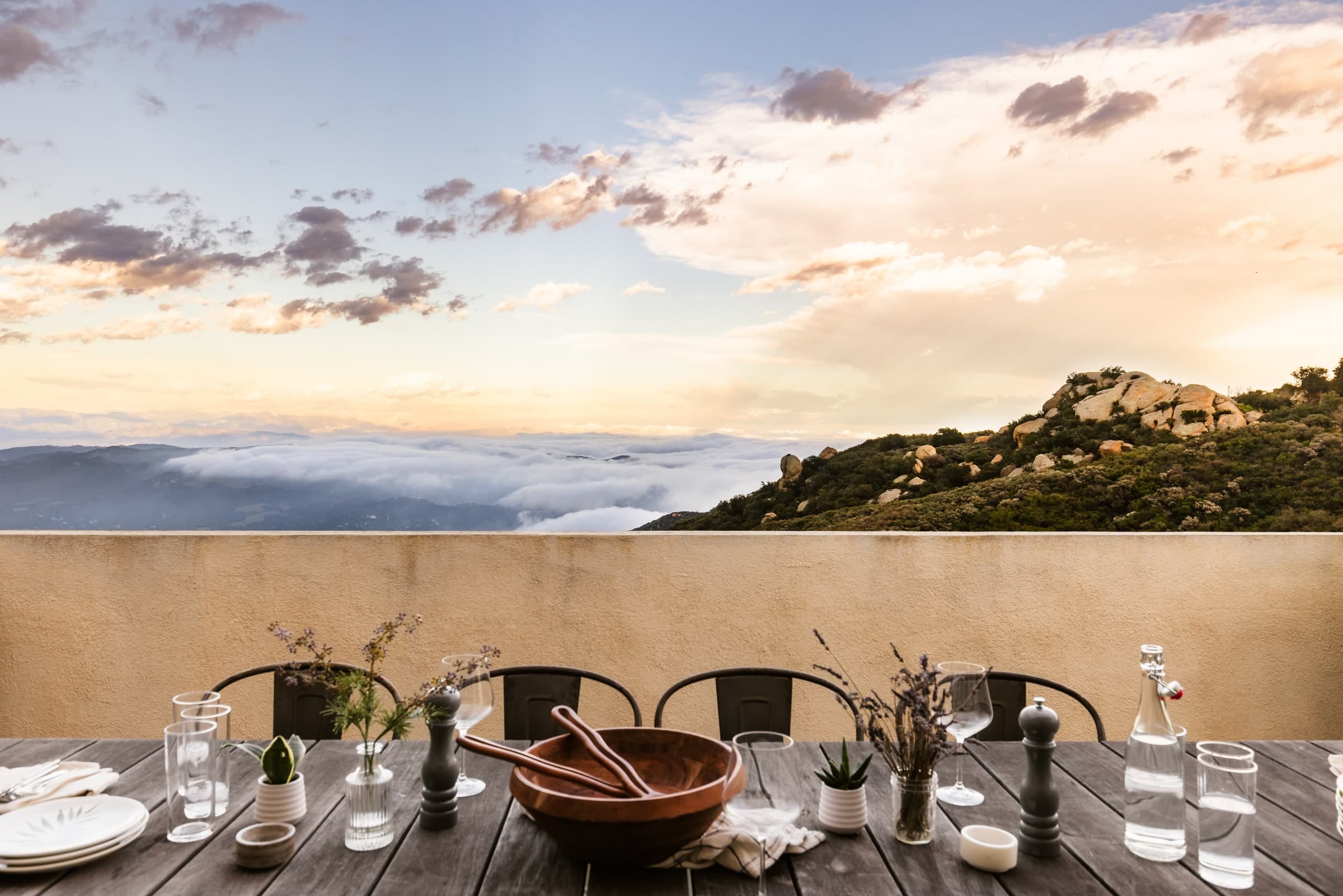 Sunset over a valley of low clouds, seen from a dining table set on a hillside terrace